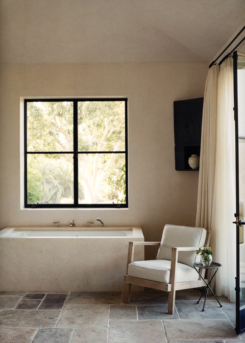 łazienka rustykalna ze skosami w kamienną podłogą, zabudowaną wanną, duże okno i wyjście na taras dodaje przytulny klimat pokoju kąpielowego w barwach kremu