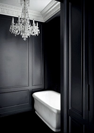 stylizowana czarna łazienka  z czarną boazerią na ścianach z białą wanną i kryształowym żyrandolem